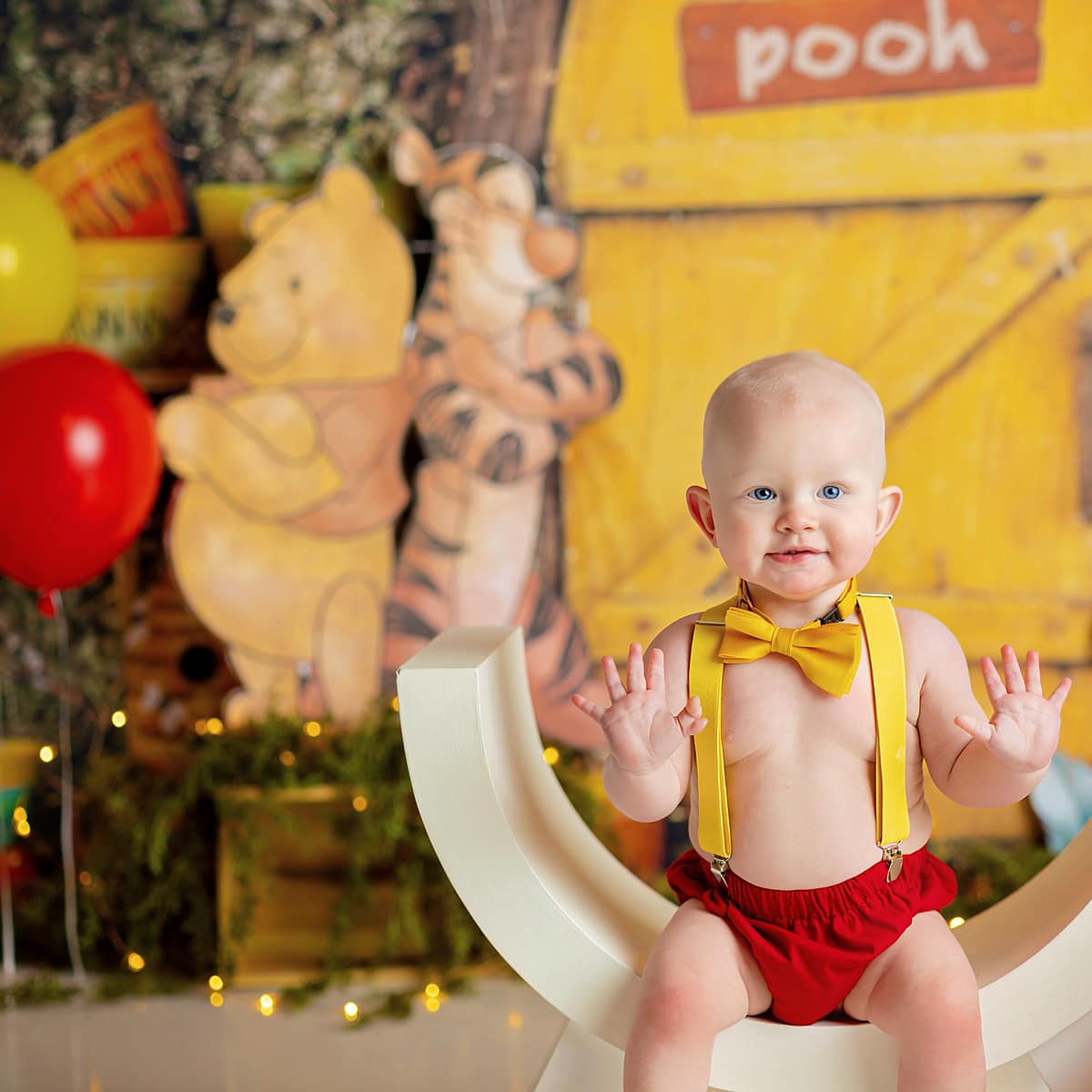 Baby boy sitting in an arched chair in a Winnie the Pooh themed set