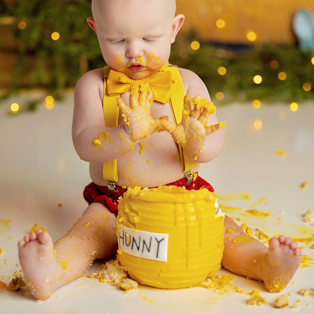 Cake Smash Session. A baby boy is playing with a yellow cake that looks like a pot of honey