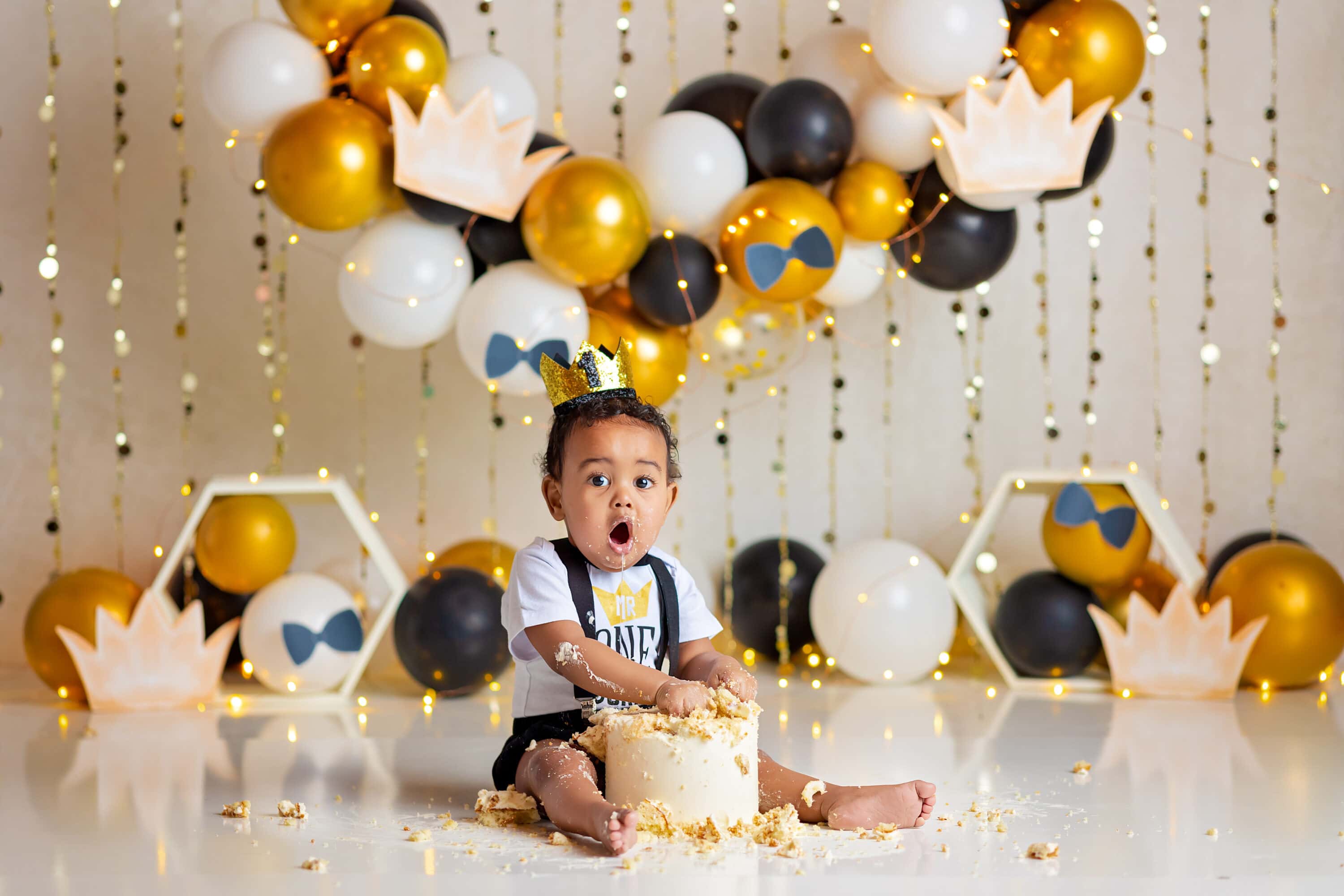 Baby boy looking surprised with hands in cake