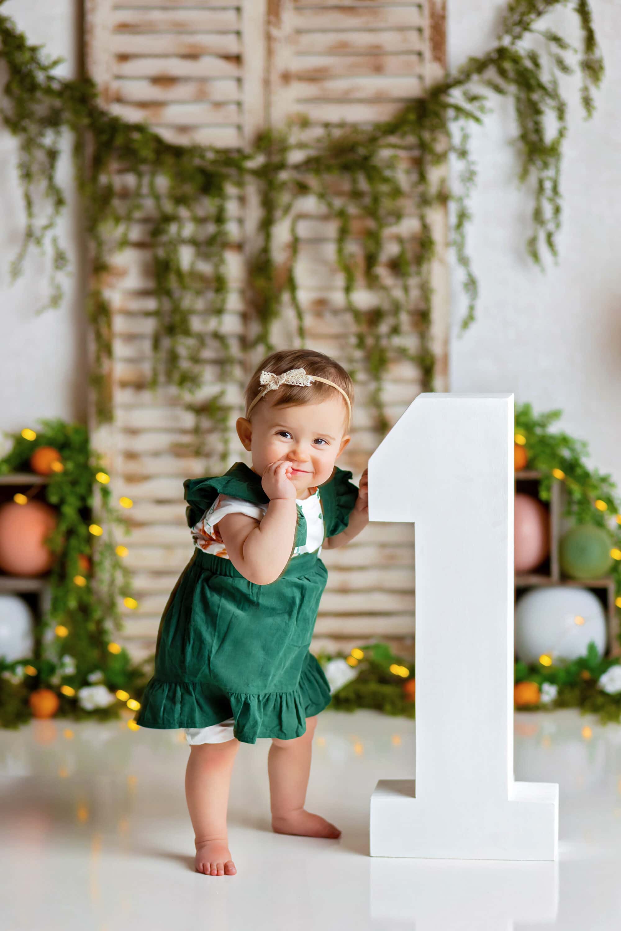 Baby girl at Cake Smash standing next to wooden number one