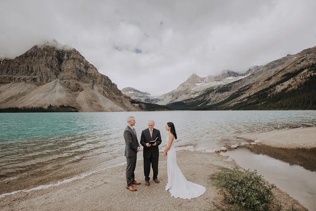 A bride and a groom eloping at the beach at Bow Lake, in Banff National Park Alberta.